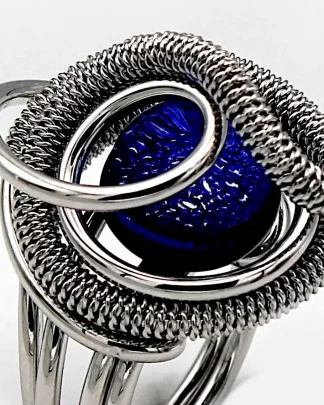 swirling silver tone mound ring holding a blue Murano glass ring