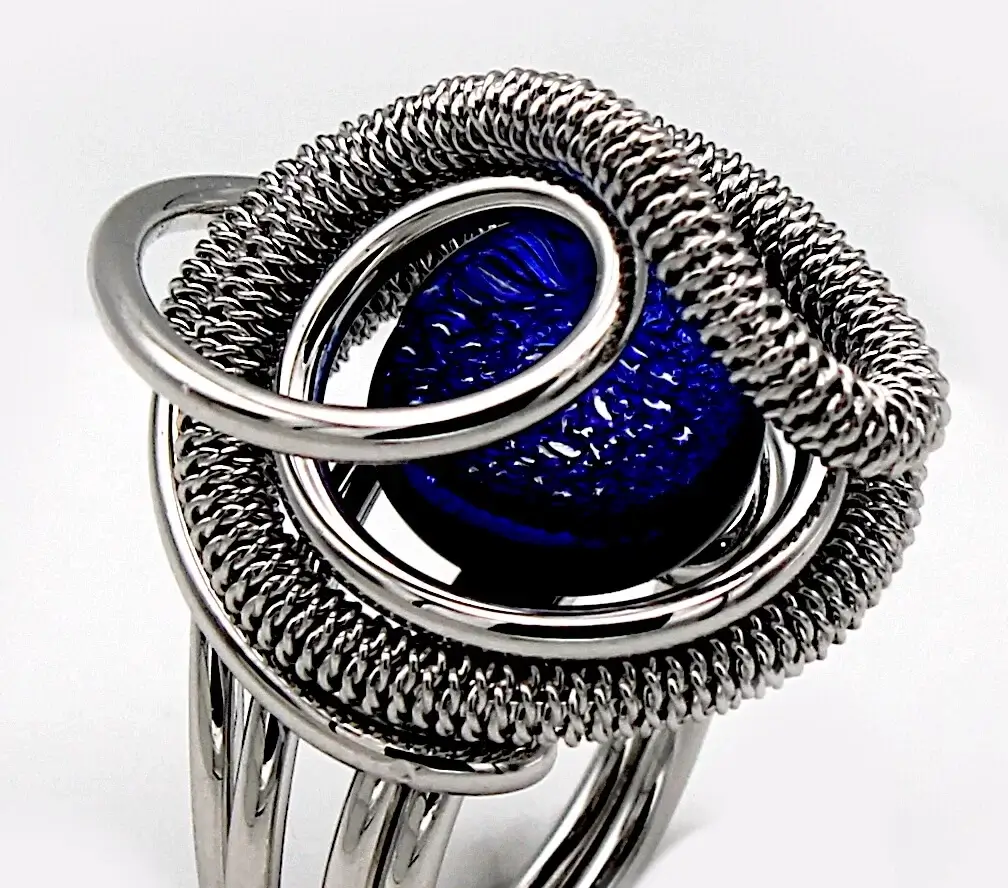 swirling silver tone mound ring holding a blue Murano glass ring