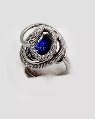Swirls of silver tone rhodium nestle a mound of Murano glass blue bead