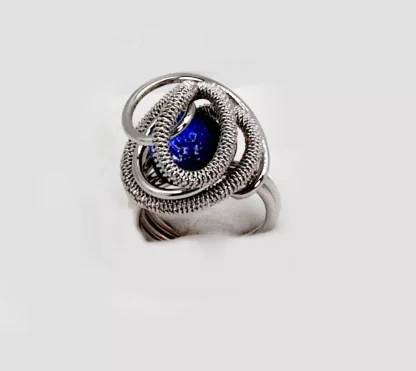 Swirls of silver tone rhodium nestle a mound of Murano glass blue bead
