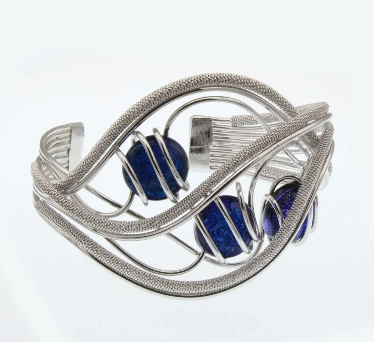 silver tone cuff bracelet in wrapped wire, hand tooled rhodium in an elaborate wave design with three royal blue Murano glass beads