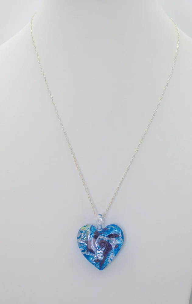 Murano Blue Cyclone Heart Pendant is a shimmering statement of  silver in on a bed of blue tones Murano glass on an 18 inch silver chain