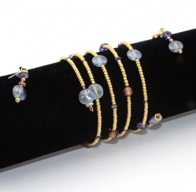 Multi-wrap gold seed bead bracelet with blue Murano glass beads on a black display